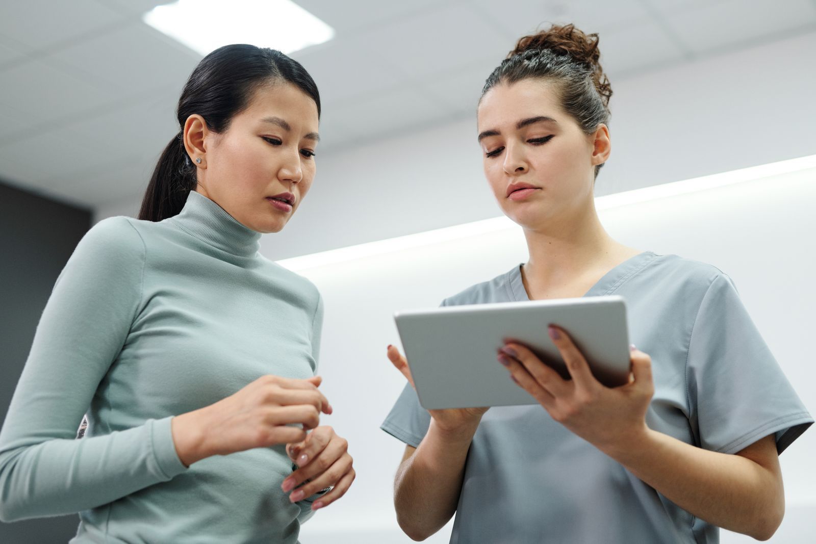 A clinician and patient reviewing information on a digital tablet — the healthcare workflows Vasuki Indicus connects
